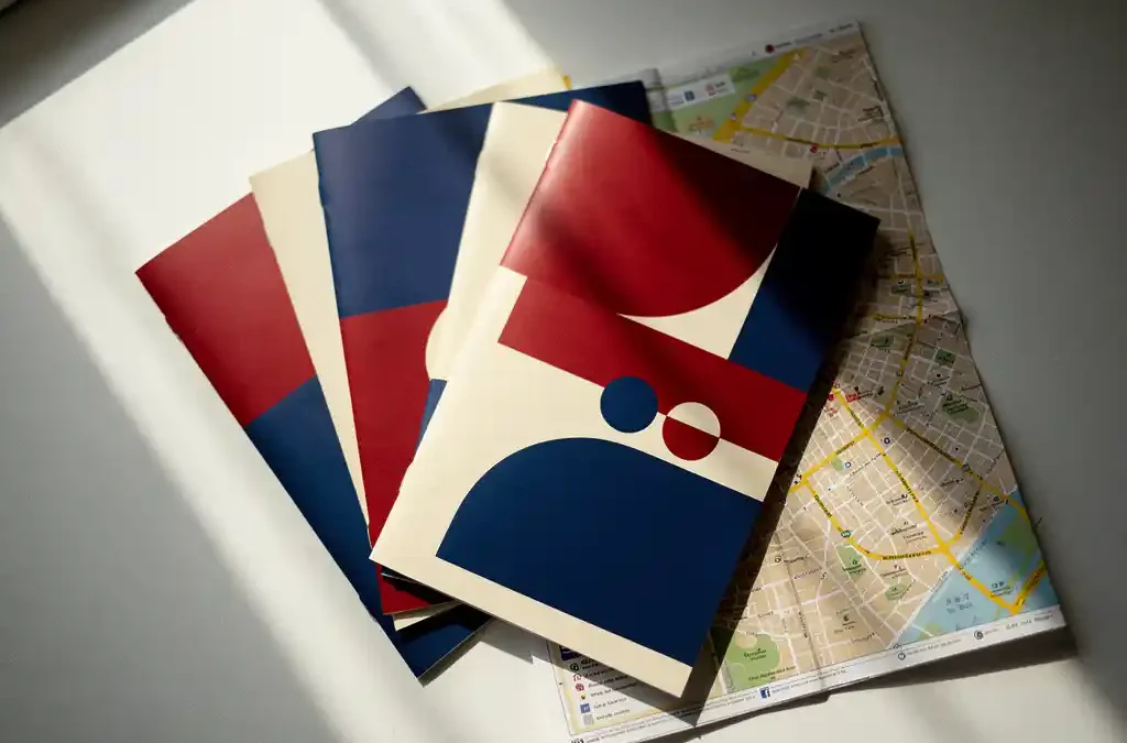 Meertalige promotiefolder en verkoopmateriaal uitgewaaierd op wit oppervlak, met Europese stadskaart eronder, bovenaanzicht.